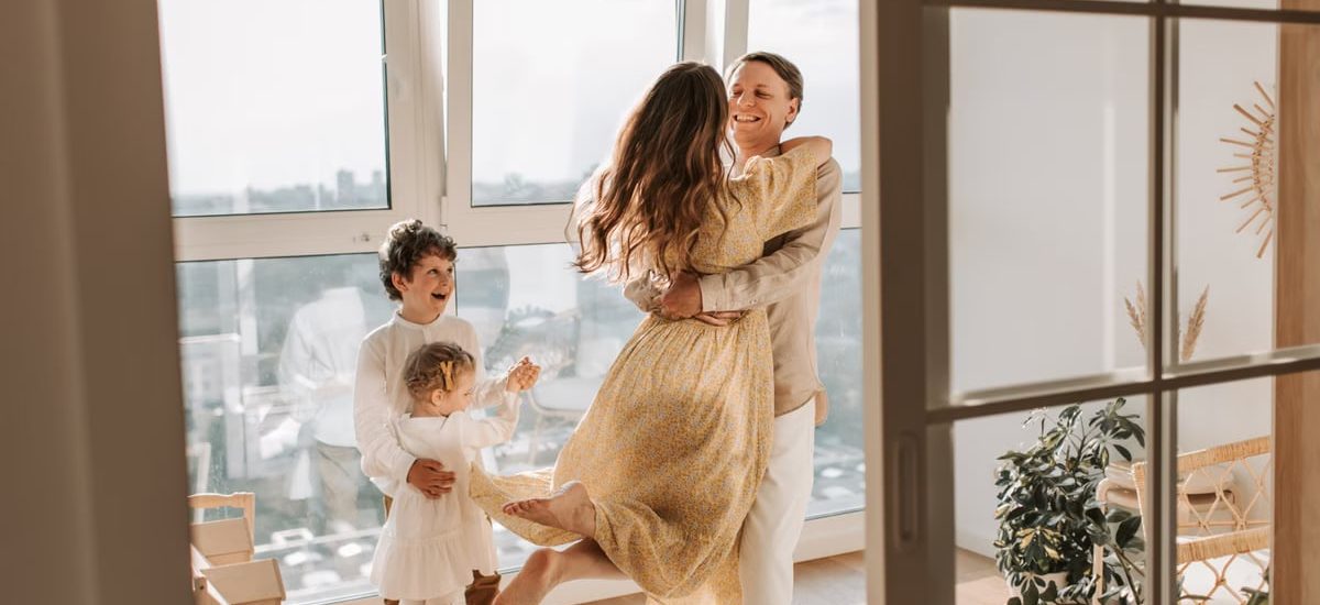 A joyful family embraces in a sunlit modern apartment, celebrating togetherness and love.